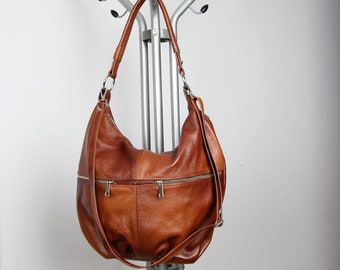 May include: A brown leather hobo bag with a long strap and multiple zippered compartments.