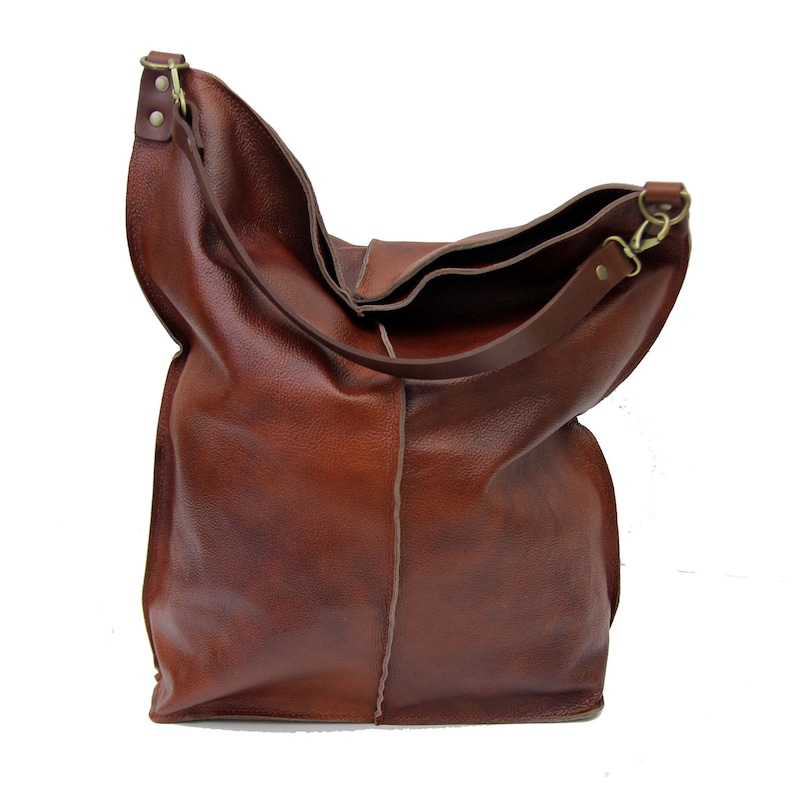 May include: A large brown leather tote bag with a single strap. The bag has a slouchy, casual look and is made of a soft, supple leather.