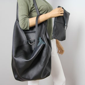 May include: A large black leather tote bag with a silver ring detail and a smaller black leather clutch bag.