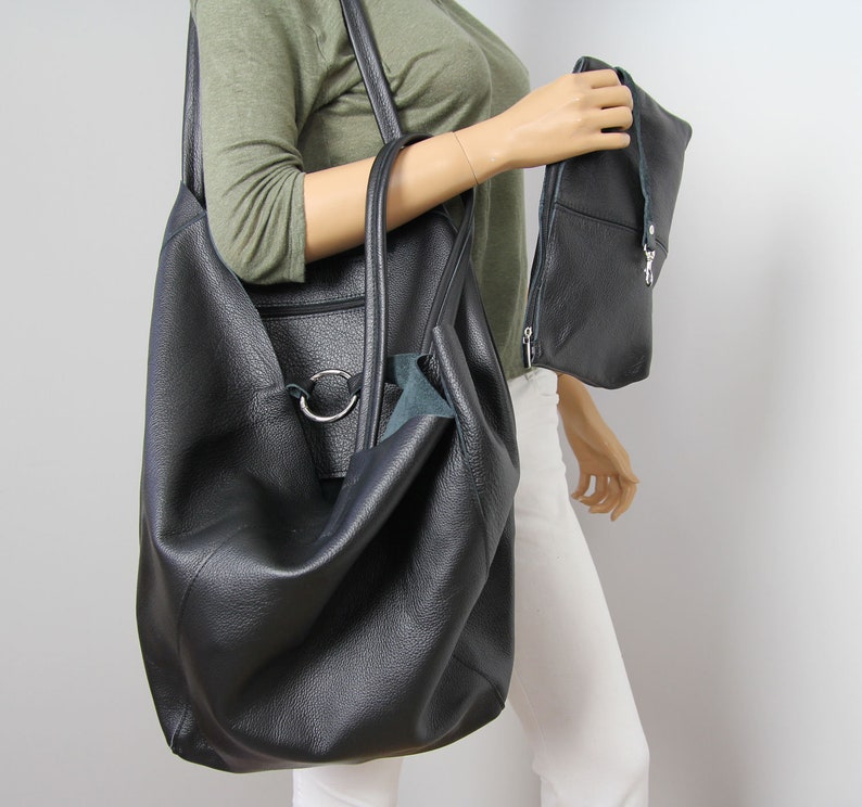 May include: A large black leather tote bag with a silver ring detail and a smaller black leather clutch bag.