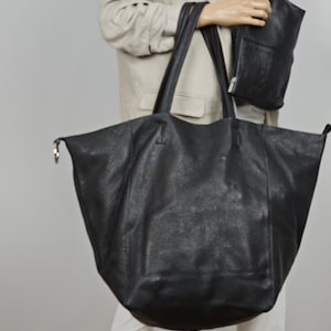 May include: A large black leather tote bag with two handles. The bag is made of a textured leather and has a slightly slouchy shape.