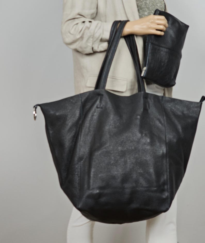 May include: A large black leather tote bag with two handles. The bag is made of a textured leather and has a slightly slouchy shape.
