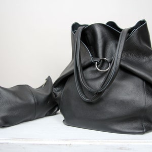 May include: Two black leather bags, one large tote bag with a ring handle and a smaller pouch with a zipper.