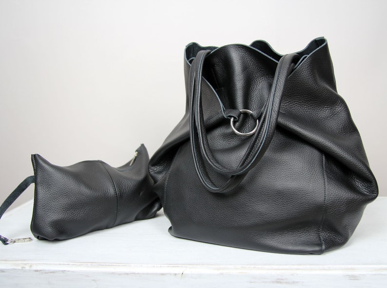 May include: Two black leather bags, one large tote bag with a ring handle and a smaller pouch with a zipper.
