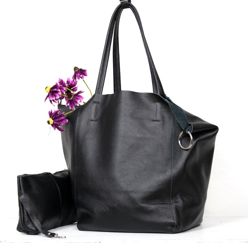 May include: A large black leather tote bag with a smaller black leather pouch attached to the side. The tote bag has a green leather strap and a silver ring.