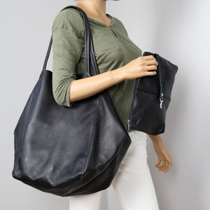 May include: A large black leather tote bag with a smaller black leather clutch bag. Both bags have a textured finish.