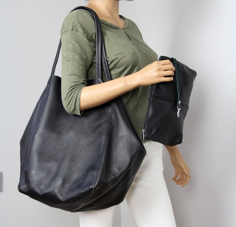 May include: A large black leather tote bag with a smaller black leather clutch bag. Both bags have a textured finish.