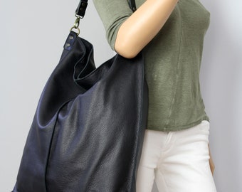 May include: A large black leather tote bag with a long adjustable strap. The bag has a slouchy, casual look and is perfect for everyday use.