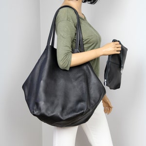 May include: A large black leather tote bag with a smaller black leather clutch. The tote bag has a slouchy, unstructured shape.