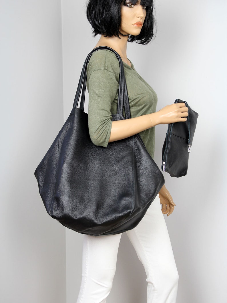 May include: A large black leather tote bag with a smaller black leather clutch. The tote bag has a slouchy, unstructured shape.