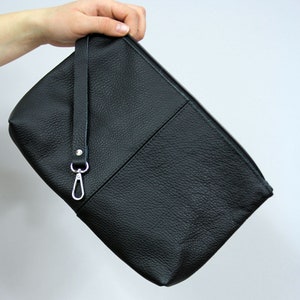May include: A black leather clutch with a zipper closure and a silver chain strap.