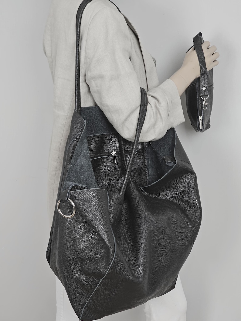 May include: A large black leather tote bag with a smaller black leather pouch attached to the side. The tote bag has a long strap and a top handle.