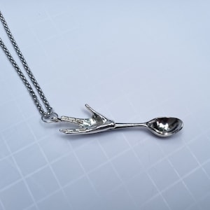 Peut inclure: Un collier argenté avec un pendentif en forme de cuillère. Le manche de la cuillère est façonné comme une main faisant le salut vulcain. La chaîne est une fine chaîne de câble argentée. La cuillère mesure environ 15 cm de long.