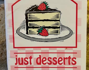 May include: A booklet with a white and pink chequered pattern and a red border. The cover shows a cake illustration with strawberries and the words "just desserts" in red.
