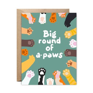 Peut inclure: Une carte verte avec un cercle d'empreintes de pattes autour du texte "Big round of a-paws".