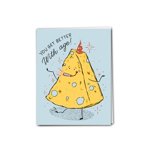 Peut inclure: Une carte de vœux bleu clair avec une illustration de dessin animé d'un morceau de fromage portant un chapeau de fête et tenant un pétard. Le texte "You get better with age!" est écrit en noir sur la carte.