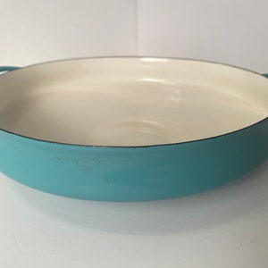 May include: A light blue enamel cast iron skillet with two handles. The skillet is empty and has a white interior.