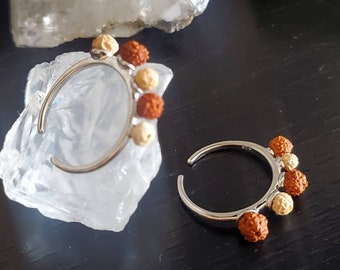 May include: Two silver rings with a row of brown and beige beads. The rings are open and have a simple design.