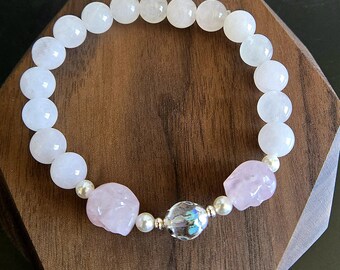 May include: A white and pink beaded bracelet with a clear crystal charm and two pink skull beads.