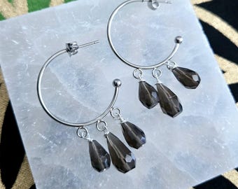 May include: Silver hoop earrings with three smoky quartz teardrop charms dangling from each hoop.