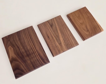 Peut inclure: Trois planches rectangulaires en bois disposées par taille décroissante de gauche à droite. Chaque planche présente un motif de grain de bois naturel distinct dans des nuances de brun variées, allant d'un brun foncé profond à un ton brun doré plus clair.
