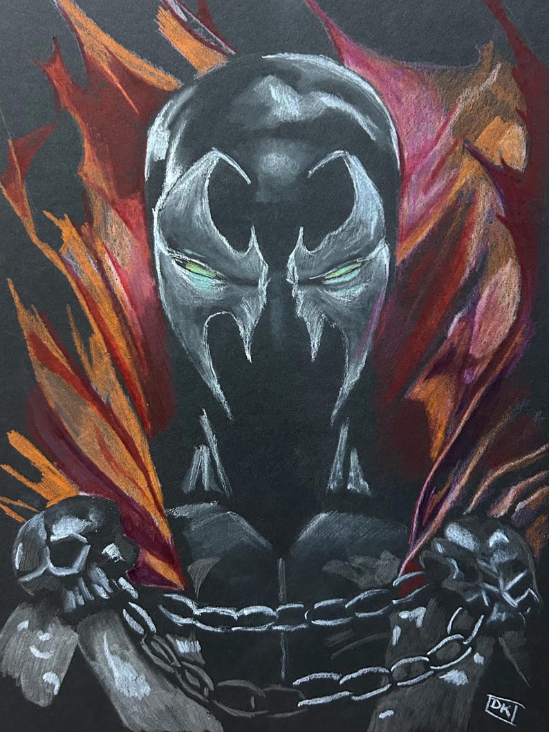 May include: A drawing of the comic book character Spawn, rendered in white and gray on a black background. The character's mask and chest are visible, with a red and orange cape. A chain and skull details are also present.