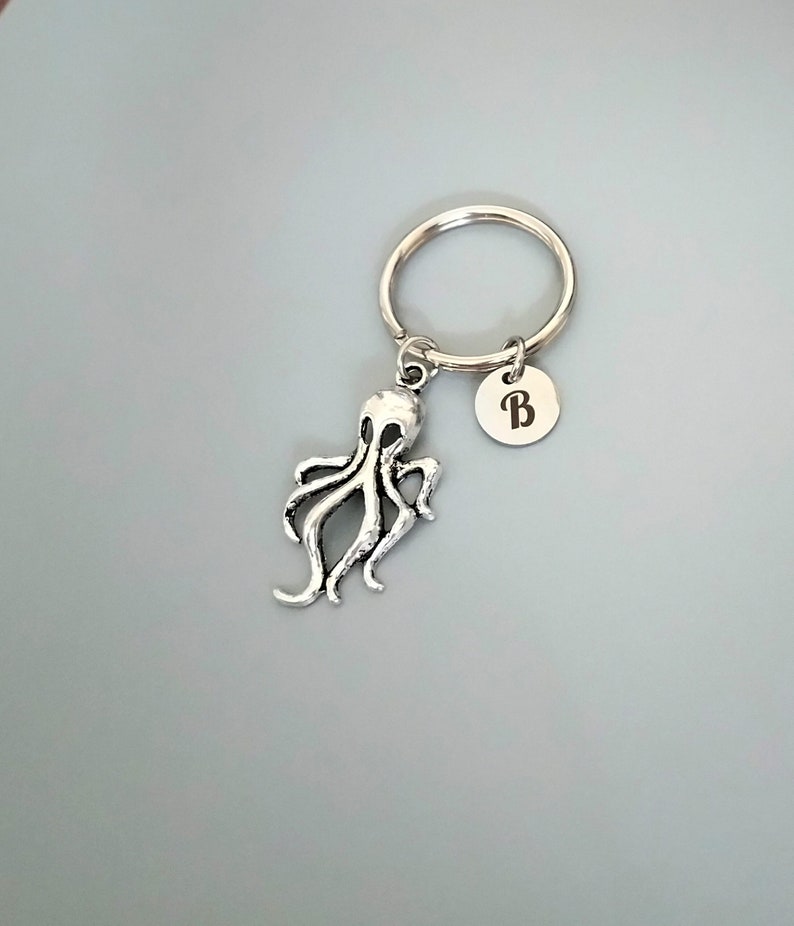 Puede incluir: Llavero de pulpo plateado con un llavero plateado y un dije plateado con la letra "B" grabada.