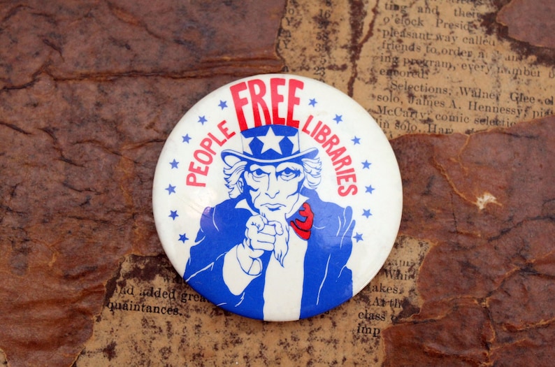 Puede incluir: Un bot&oacute;n blanco con una ilustraci&oacute;n azul y roja del T&iacute;o Sam apuntando con el texto "PEOPLE'S FREE LIBRARIES" alrededor de la imagen.
