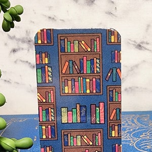 May include: A blue and brown bookmark with a repeating pattern of bookshelves filled with colorful books.
