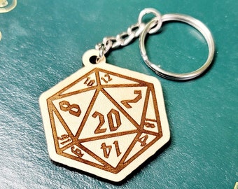 May include: A wooden keychain shaped like a twenty-sided die with numbers 1 through 20 engraved on each side. The keychain is attached to a silver key ring.