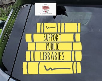 Może przedstawiać: Żółta naklejka winylowa na tylnej szybie samochodu. Naklejka przedstawia stos książek z napisem "Support Public Libraries".