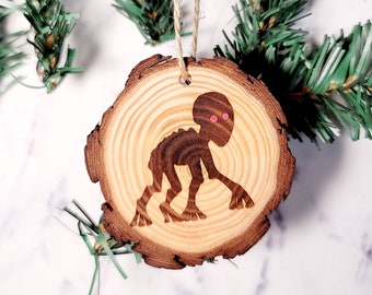 May include: A wooden Christmas ornament shaped like a tree trunk with a silhouette of a creature with red eyes.