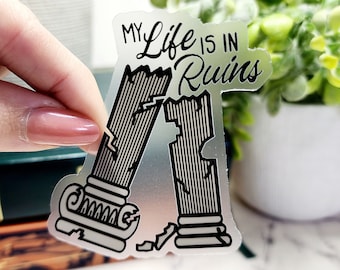May include: A clear sticker with a black design of two broken columns with the text "My Life is in Ruins".