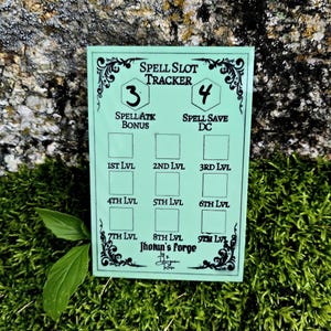 May include: A light green rectangular spell slot tracker card with black text and decorative borders. The card features sections for Spell Atk Bonus, Spell Save DC, and levels 1st through 9th, with the text Jhotun's Forge printed at the bottom.