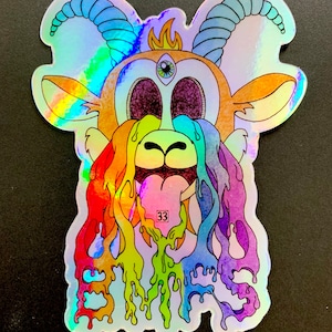 May include: A holographic sticker featuring a cartoon goat with rainbow-colored dripping paint and the word "EVILS" written in the paint. The goat has a third eye and horns.