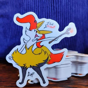 May include: A die-cut sticker featuring a cartoon fox-like character in yellow, orange, and white, holding a wand. The sticker has the text "I cast Fireball!" and the artist's signature.