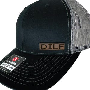 May include: Black and grey trucker hat with a brown leather patch that says "DILF".