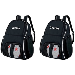 May include: Two black sports bags with white accents and mesh pockets. The bags have a zippered compartment for a ball and are personalized with the names "James" and "Charles".