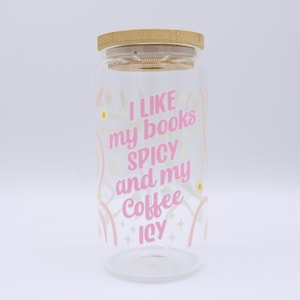 May include: A clear glass tumbler with a wooden lid. The tumbler has pink text that reads "I LIKE my books SPICY and my Coffee ICY". The design includes pink and yellow decorative elements.