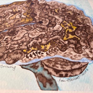 May include: A watercolour painting of a brain, rendered in shades of brown and yellow, with intricate leaf-like designs. The artwork features the word "Growing" and a signature. The brain is set against a light blue backdrop.