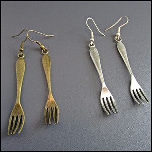 May include: Two pairs of fork earrings, one pair is silver and the other is gold.