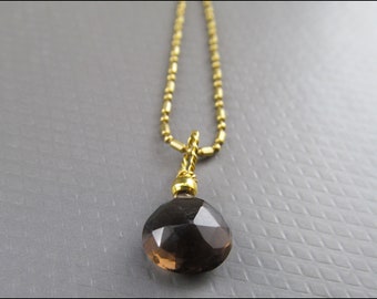 May include: A gold chain necklace with a faceted smoky quartz pendant.