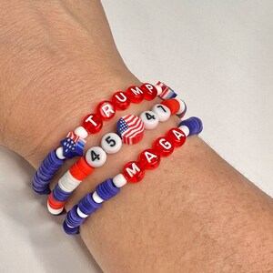 May include: Three beaded bracelets with red, white, and blue beads. The top bracelet spells "TRUMP" in red beads. The middle bracelet has white beads with the numbers "45" and a small American flag bead. The bottom bracelet spells "MAGA" in red beads.