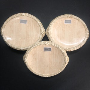 May include: Three white ceramic plates with a decorative rim and a marbleized design. Each plate has a small label with the text "Croscill Home" printed on it.