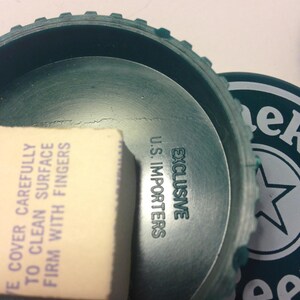May include: Green plastic lid with the text "EXCLUSIVE US IMPORTERS" and a white sticker that says "E COVER CAREFULLY TO CLEAN SURFACE FIRM WITH FINGERS"