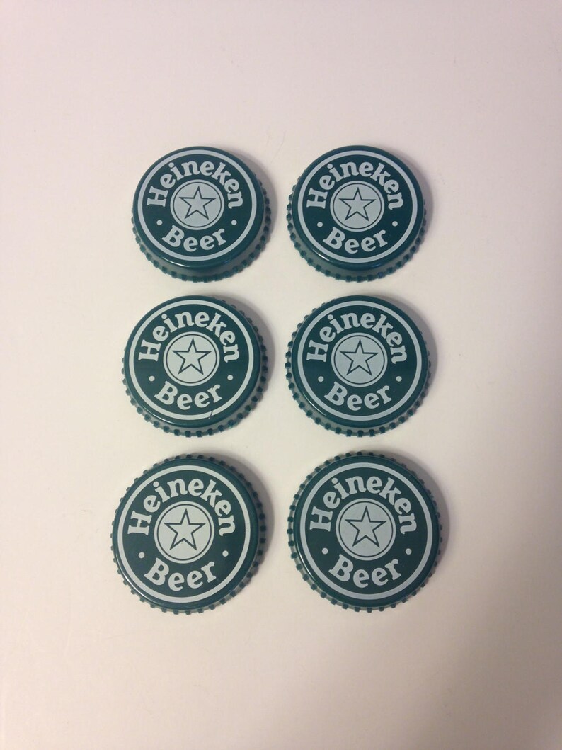 May include: Six green bottle caps with the Heineken logo and the words "Heineken Beer" in white.