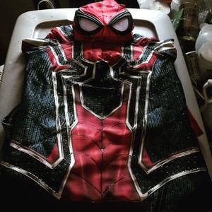 May include: A red and black Spider-Man costume with a black and white spider web design. The costume has a matching mask with a black and white spider web design.