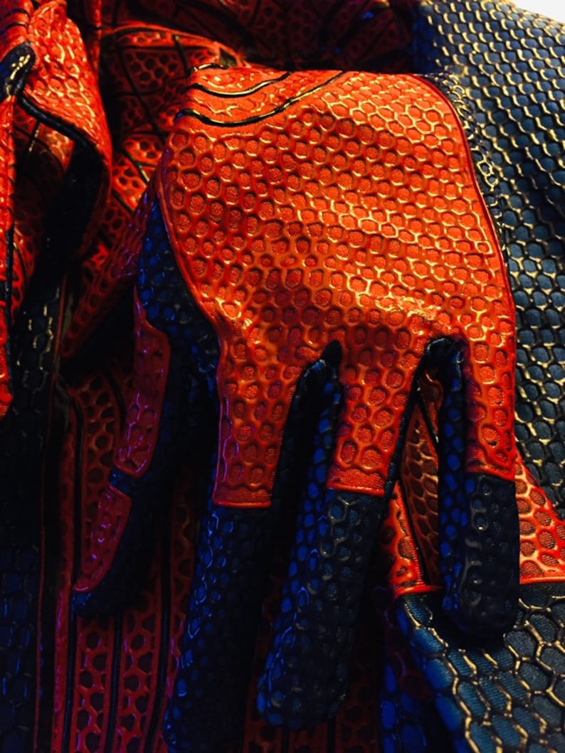 May include: Close-up of a red and blue fabric with a honeycomb pattern. The fabric is textured and has a glossy finish.