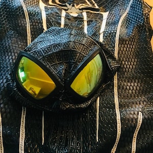 May include: Black and white Spider-Man costume with a black mask featuring yellow lenses. The costume has a web pattern and white accents.