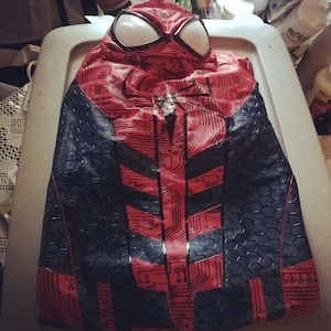 May include: Red and black Spiderman costume with a circuit board design. The costume has a hood with a large white spider eye design.